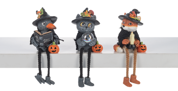 Three Halloween-themed figurines with black hats and pumpkin decorations on a white surface.