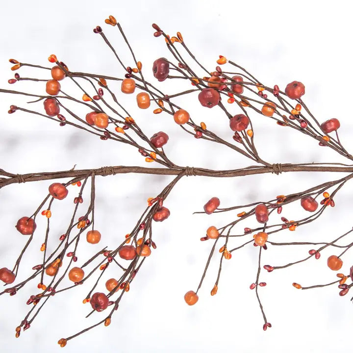 Artificial autumn branch with brown twigs, small orange berries, and red berries on a white background.