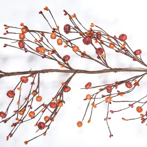 Artificial autumn branch with brown twigs, small orange berries, and red berries on a white background.