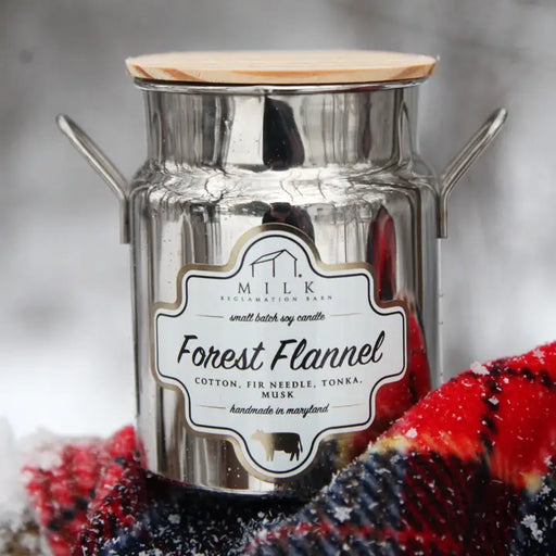 Candle in a metal container with a label on a textured surface