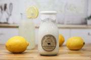 Bottle of milk with a lemon on a wooden surface