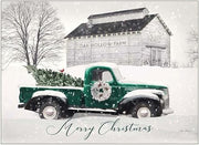 Vintage green truck with Christmas tree in front of a barn labeled 'Oak Hollow Farm' on a snowy day.