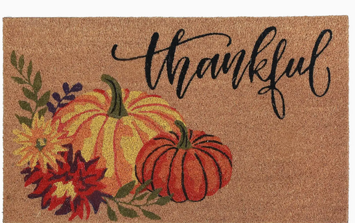 Doormat with pumpkins, flowers, and 'thankful' text on a brown background
