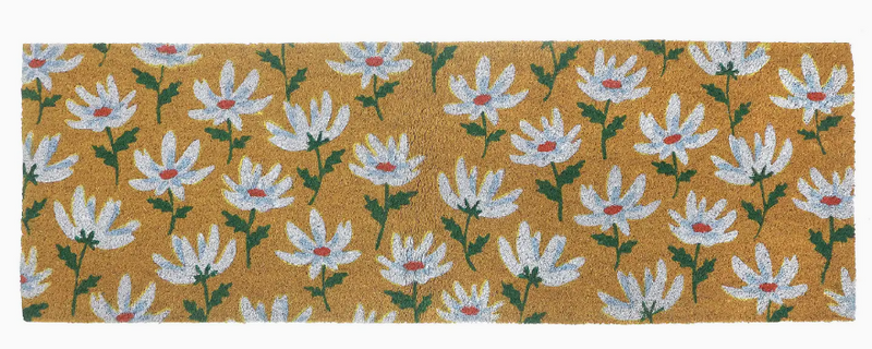 Floral patterned doormat with white flowers on a mustard yellow background