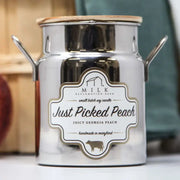 Candle jar labeled 'Just Picked Peach' by Milk Reclamation with a blurred background