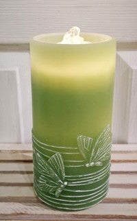 Green candle with leaf design on a wooden surface
