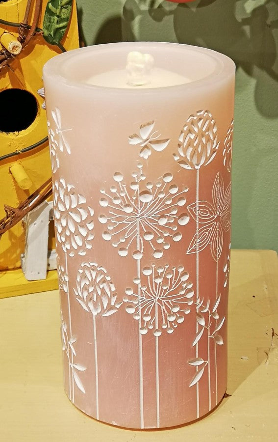 Pink candle with floral embossing on a yellow surface