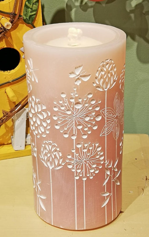 Pink candle with floral embossing on a yellow surface