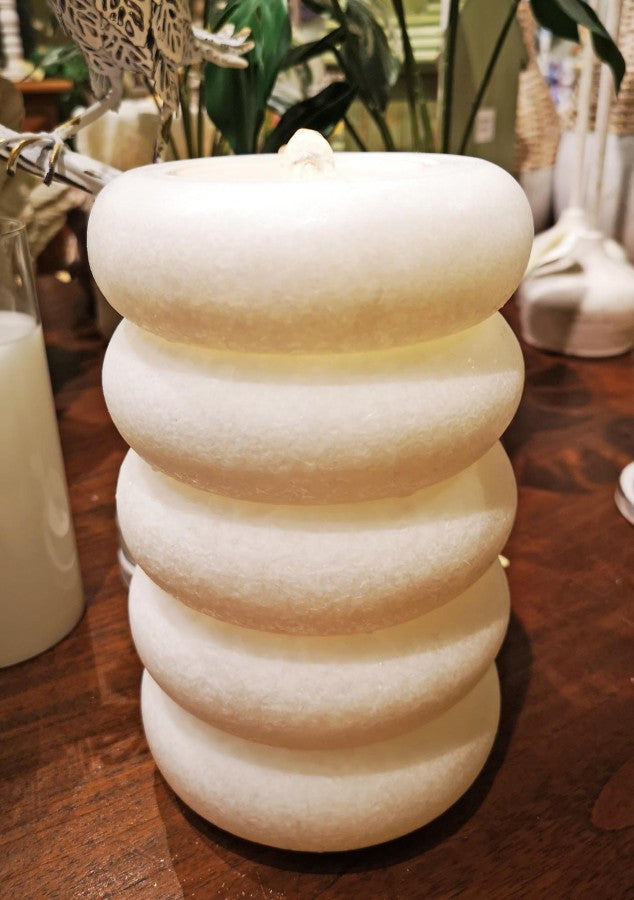 White textured candle on a wooden surface with blurred background