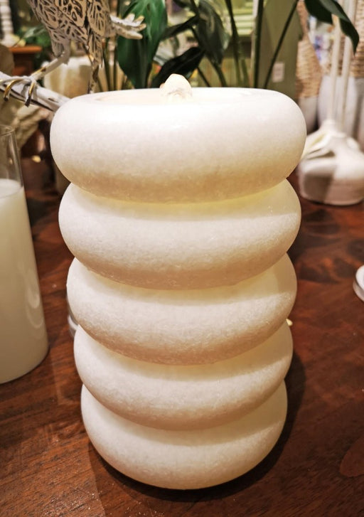 White textured candle on a wooden surface with blurred background