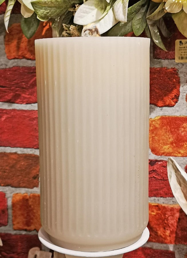 Beige cylindrical candle on a red and orange patterned surface