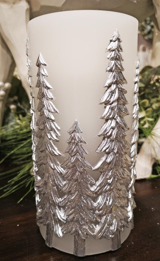 Decorative candle with silver tree embossing on a wooden surface