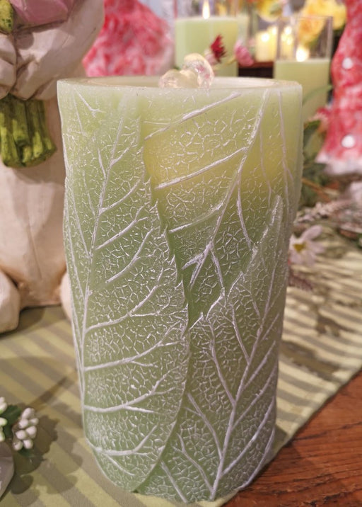 Decorative candle with leaf pattern on a table
