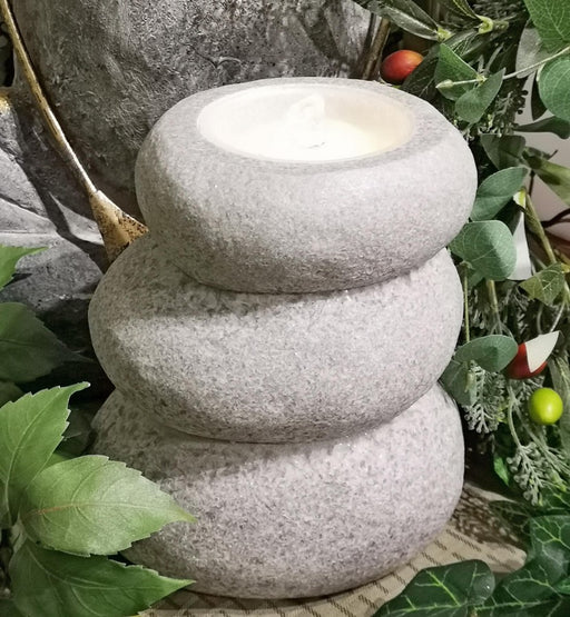 Stacked stone lantern with a light inside, surrounded by greenery