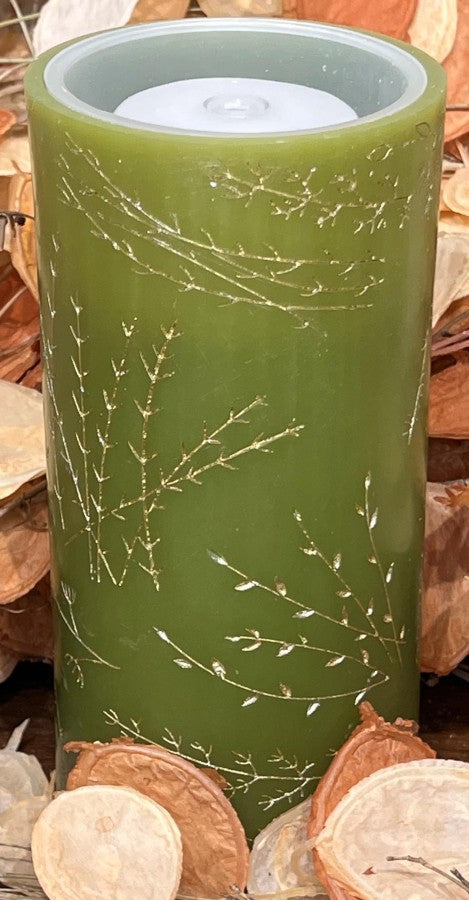 Green cylindrical candle with decorative pattern on a wooden surface