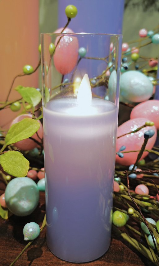 Blue candle with a lit wick surrounded by decorative eggs and branches