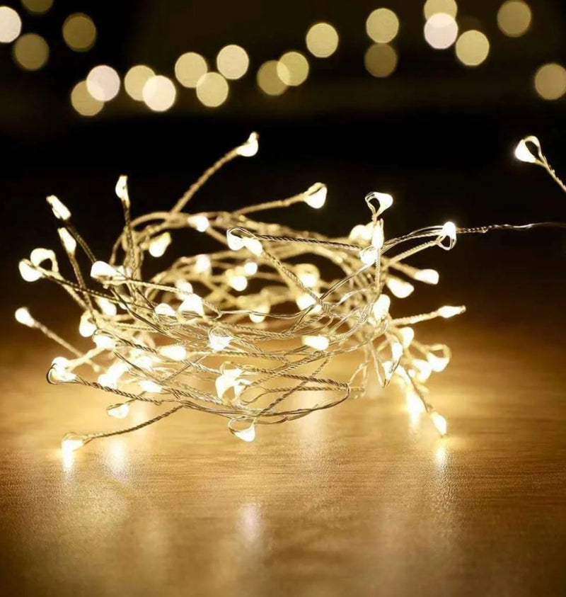 String of small lights on a reflective surface with blurred lights in the background