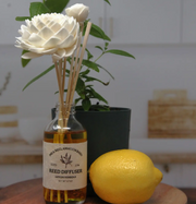 Reed diffuser with floral design next to a lemon on a wooden surface.