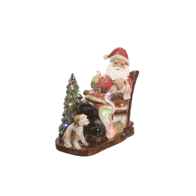 Decorative figure of Santa Claus sitting in a chair with a dog next to him, against a white background.