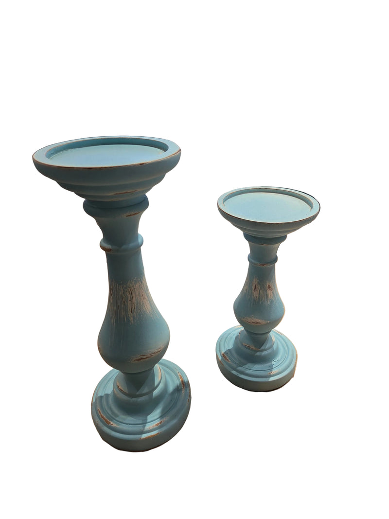 Two blue candle holders on a table with a store setting in the background.