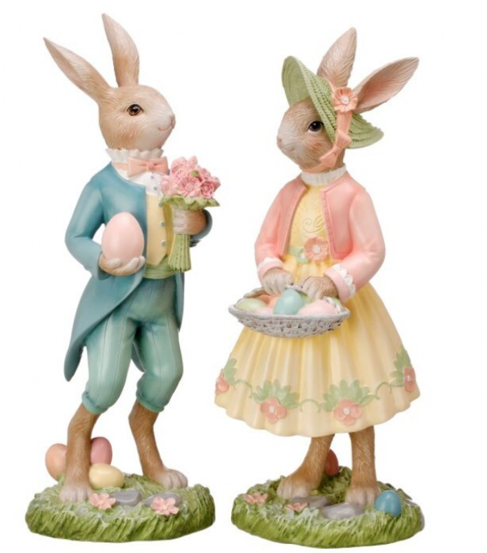 Two decorative figurines of rabbits in Easter attire on a white background