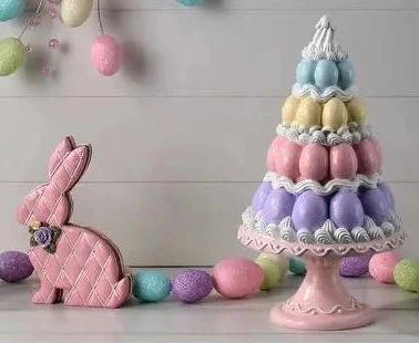 Pastel Easter decorations including a cake stand with eggs, cookies, and decorative eggs on a wooden background.