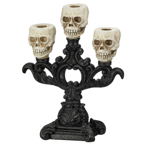 A gothic-style three-skelion candle holder with an ornate black metal base and three cream-colored skull candle cups, shown against a plain white background.