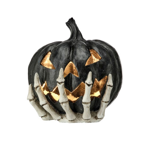 Black pumpkin with carved face and skeleton hands on a white background