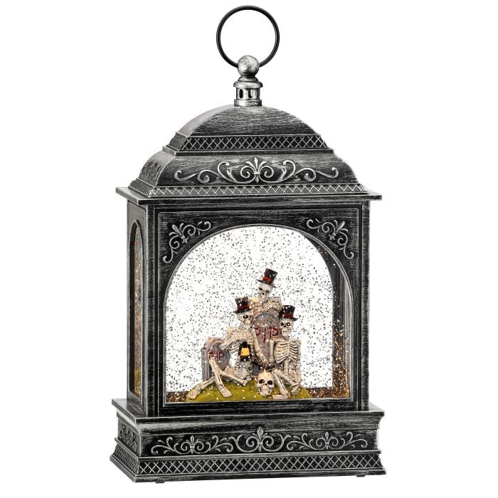 A decorative lantern-shaped snow globe with an ornate black metal frame and top loop, featuring a skeleton wedding scene with a bride and groom surrounded by snow and small skulls inside.