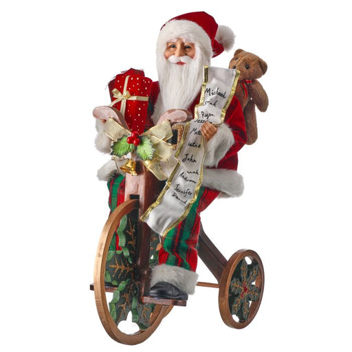 Decorative figure of Santa Claus on a tricycle with gifts and a teddy bear.