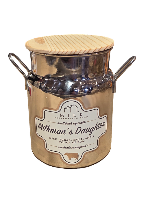 A soy wax candle in a white container designed to resemble a milk bottle, with a label that reads 'Milkman's Daughter'. The lid is wood with a silicone ring.