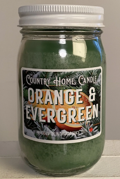 Jar of 'Orange & Evergreen' candle by Country Home Candle on a neutral background