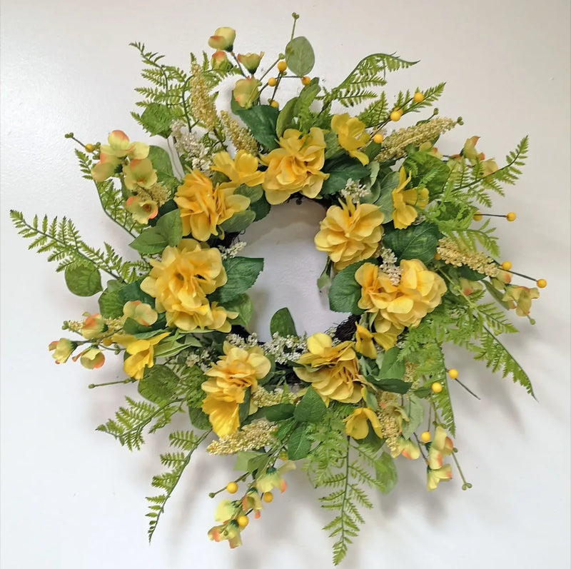 Floral wreath with yellow flowers and green leaves on a white background