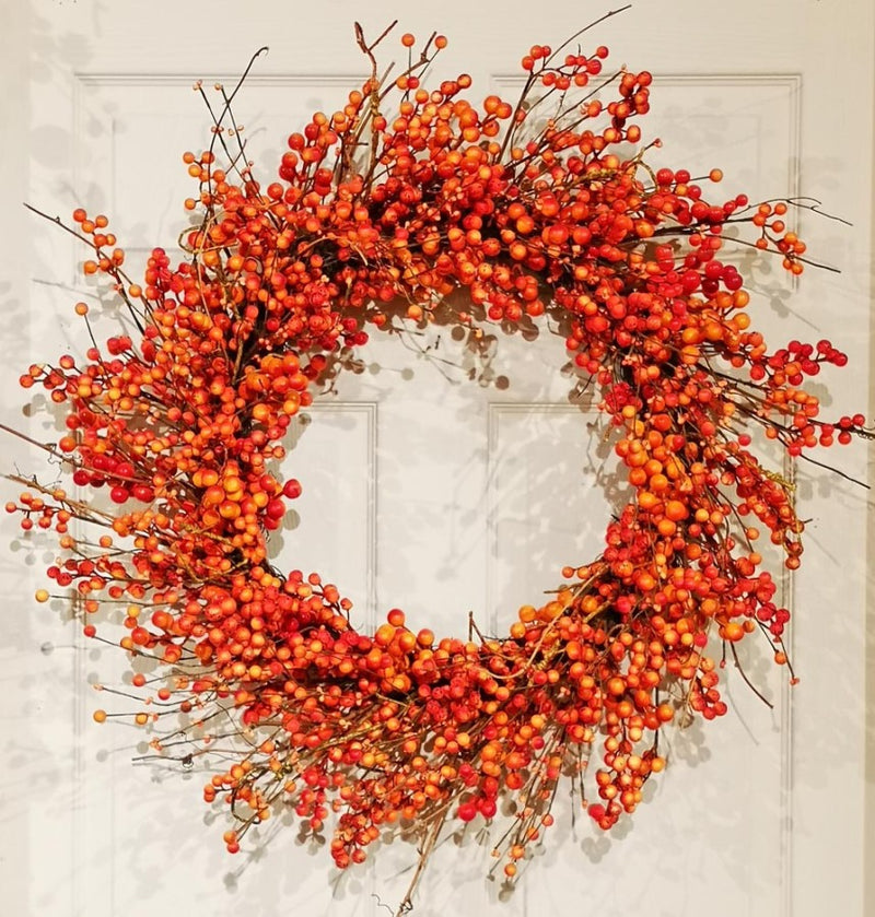 Wreath made of orange berries and branches on a neutral background