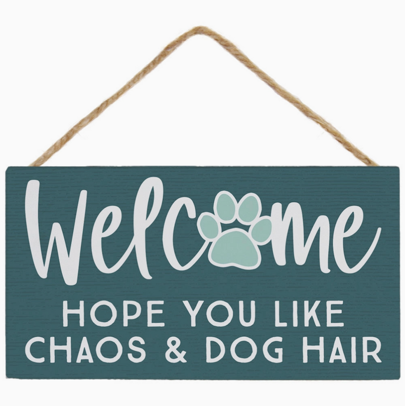 Decorative sign with text 'Welcome hope you like chaos & dog hair' on a teal background.