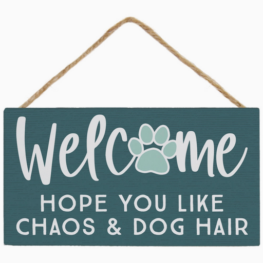 Decorative sign with text 'Welcome hope you like chaos & dog hair' on a teal background.