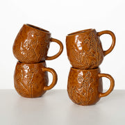 Four brown ceramic mugs with floral embossing on a white background