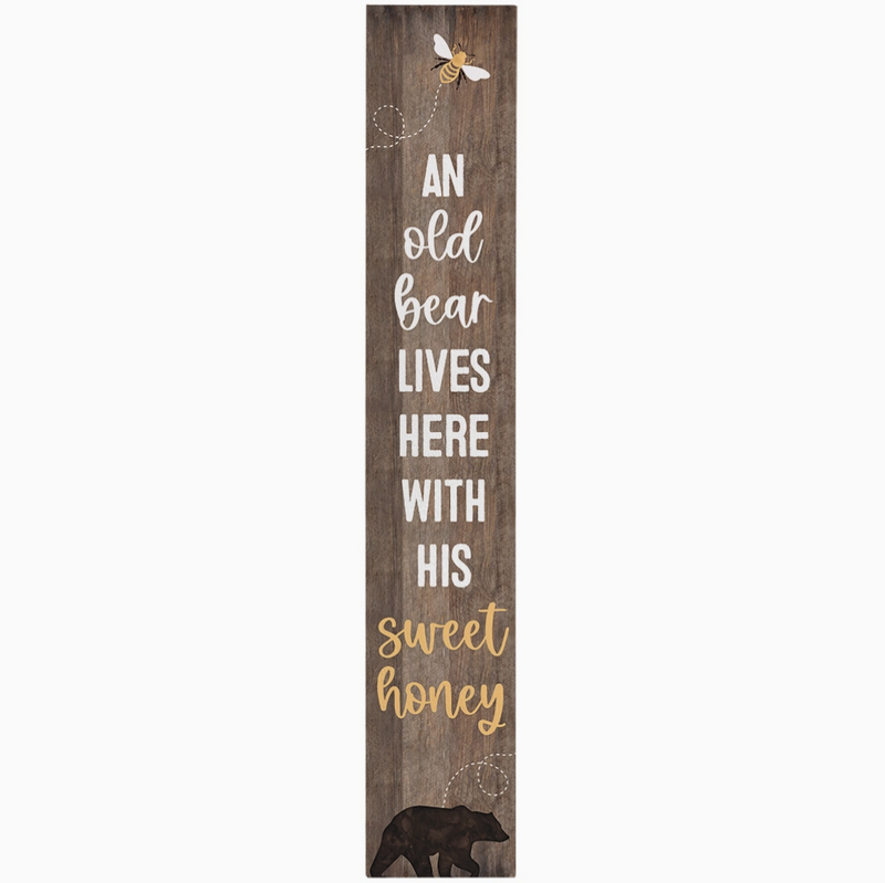 Wooden sign with text 'An old bear lives here with his sweet honey' and illustrations of a bear and a bee on a white background.