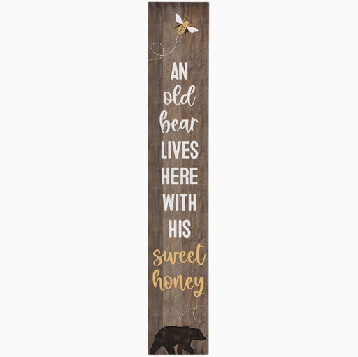 Wooden sign with text 'An old bear lives here with his sweet honey' and illustrations of a bear and a bee on a white background.