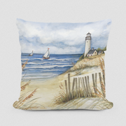 A decorative pillow with a painted beach and lighthouse scene, including sailboats and a sandy shore.