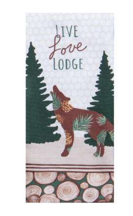 A rectangular decorative towel or fabric panel with a winter lodge theme. The design shows the words “Live Love Lodge” above a brown wolf silhouette with green pine branches, flanked by dark green pine trees on a light patterned background, with a wood-slice border at the bottom.