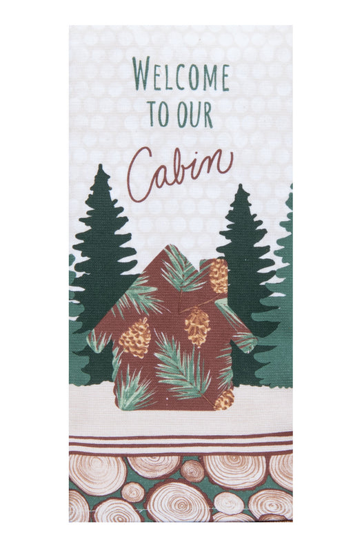 A vertical decorative tea towel with the words 'WELCOME TO OUR Cabin' above an illustrated cabin with pine trees and wood-slice patterning at the bottom.