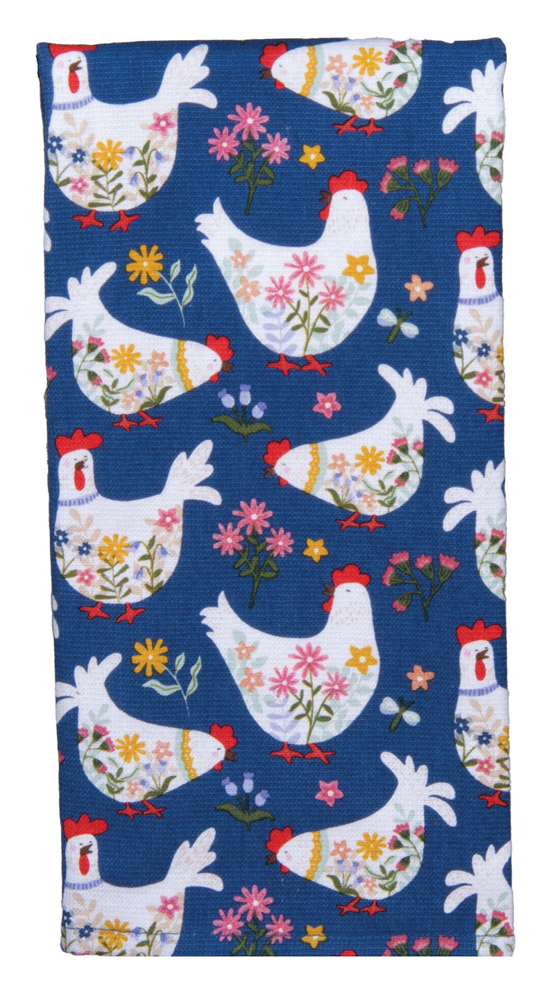 A rectangular kitchen towel with a dark blue background and a repeating pattern of white chickens decorated with colorful flowers.