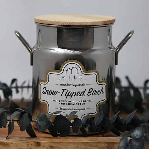 Metallic milk churn candle labeled 'Snow-Tipped Birch' with a wooden lid on a neutral background.