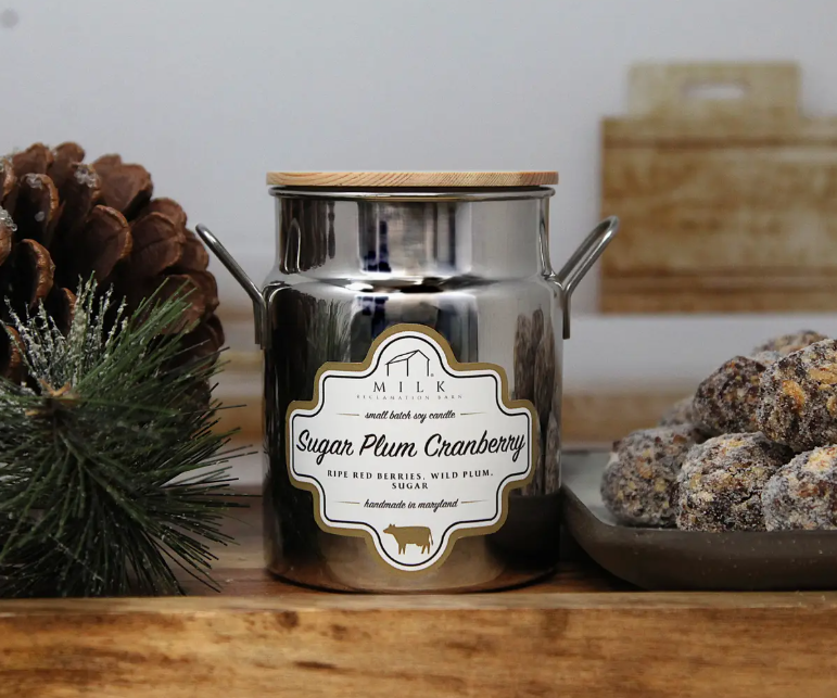 Metal milk churn with 'Sugar Plum Cranberry' label on a wooden surface with decorative elements.