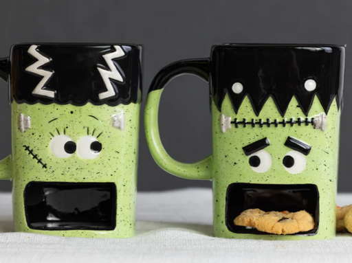 Two green Frankenstein mugs with cookie holders on a gray background
