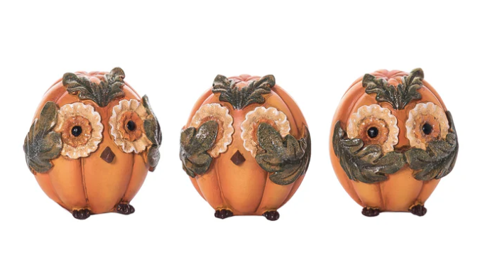 Three decorative pumpkins with owl faces on a white background