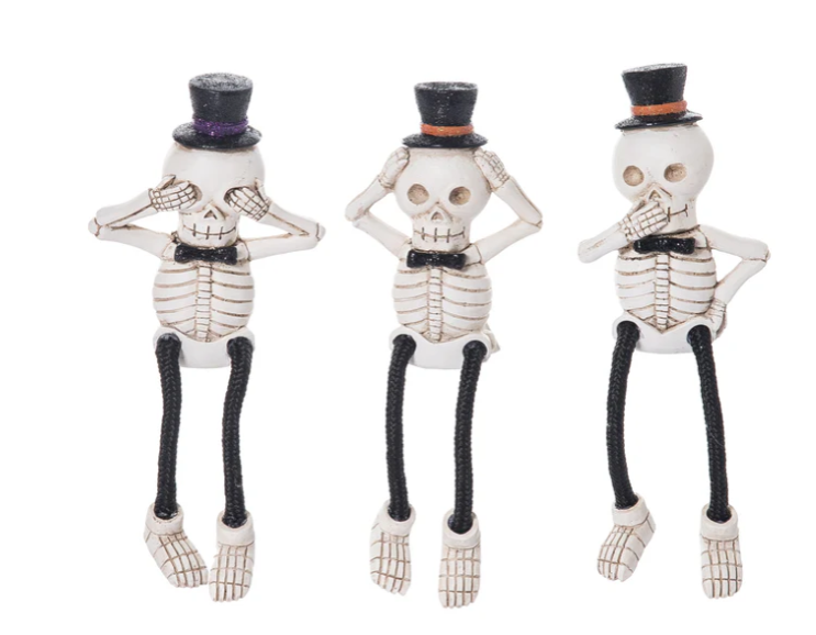 Three skeleton figurines with top hats on a white background