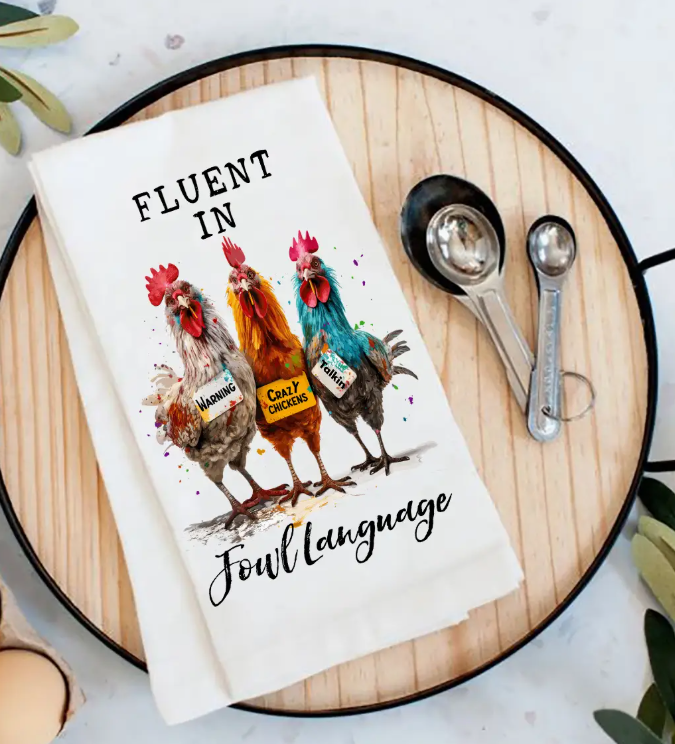 Kitchen towel with rooster design and text on a wooden cutting board