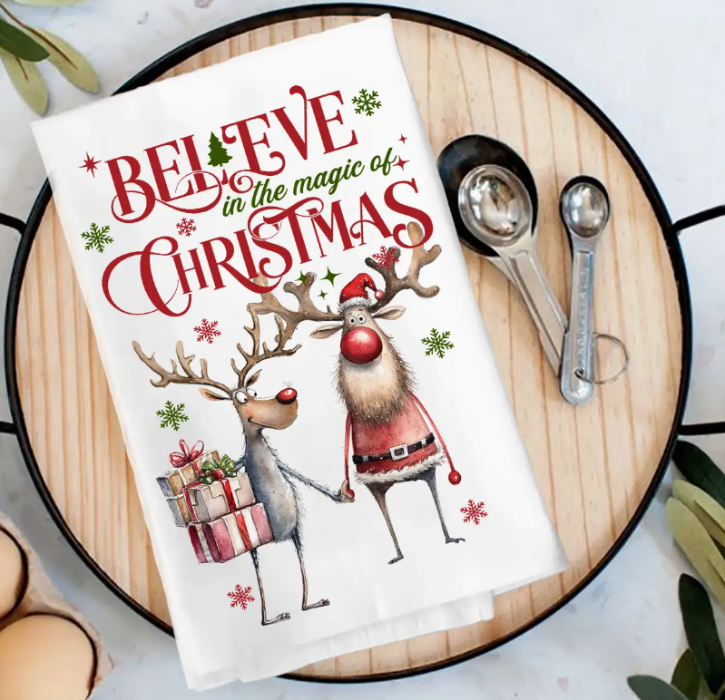 Christmas-themed towel with reindeer illustration and text on a wooden surface